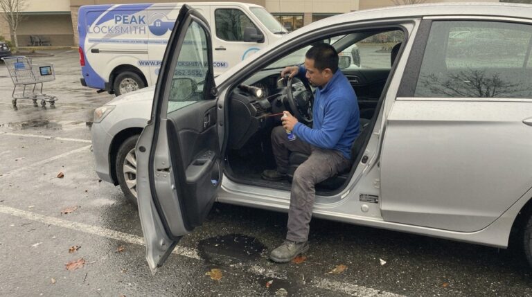 Peak Locksmith technician at the driver's door working on a car ignition that will not turn in a damp Tacoma, WA parking lot