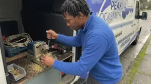 Peak Locksmith technician cutting a new house key on a key machine in the back of the service van on a Tacoma street